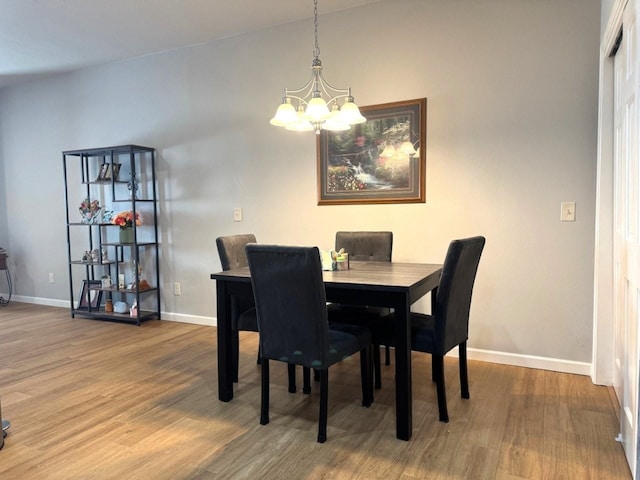 dining space with baseboards, a notable chandelier, and wood finished floors