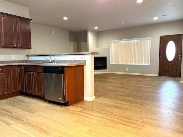 kitchen featuring open floor plan, dishwasher, light wood-type flooring, and a sink