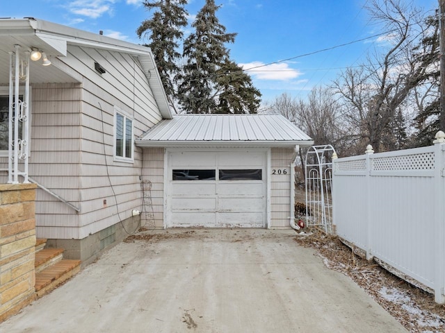 garage featuring driveway and fence