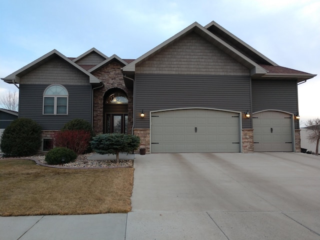 craftsman-style home featuring stone siding, driveway, and a garage