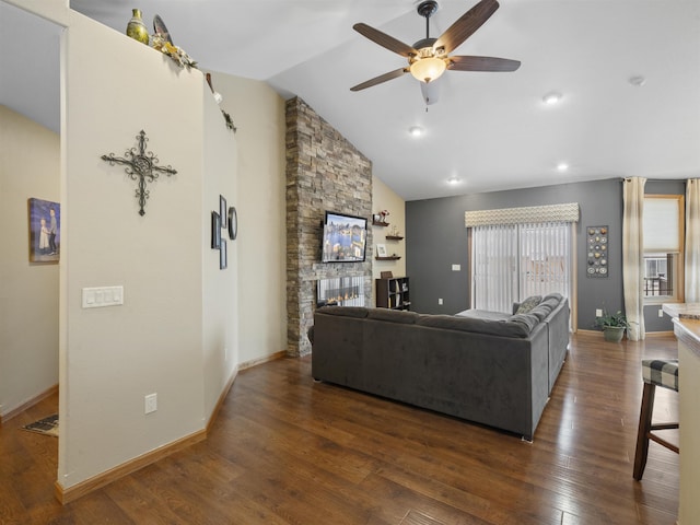 living room featuring a ceiling fan, visible vents, lofted ceiling, a stone fireplace, and wood-type flooring