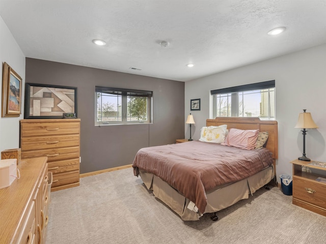 bedroom with multiple windows, light carpet, baseboards, and visible vents