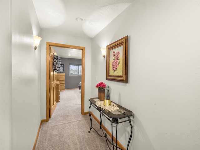 hall with baseboards and light colored carpet