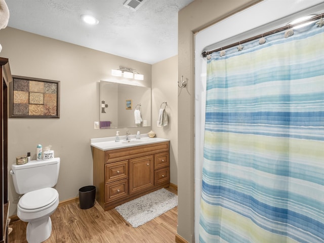 full bath featuring vanity, toilet, wood finished floors, and a textured ceiling