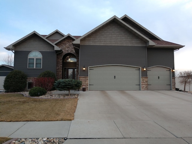 craftsman-style house featuring driveway, a garage, and stone siding