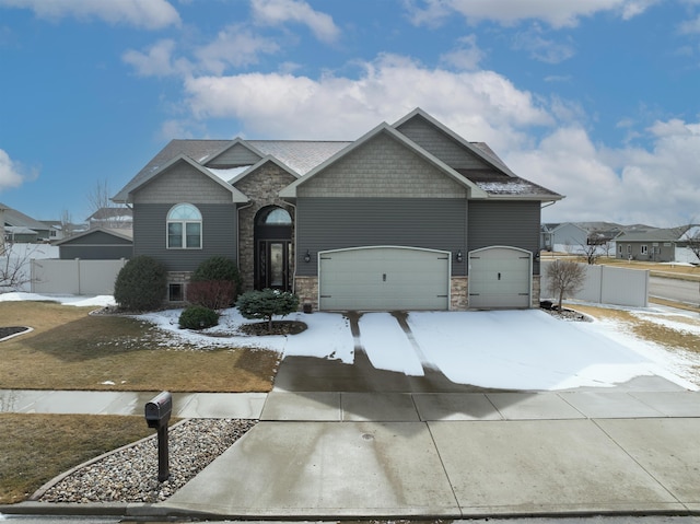 craftsman-style house with a gate, stone siding, driveway, and fence