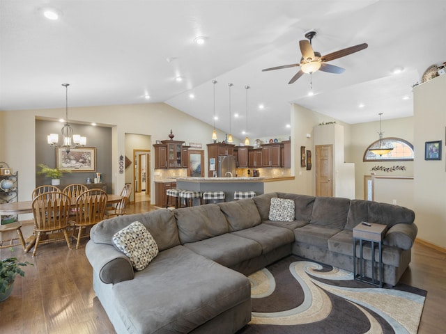 living room with ceiling fan with notable chandelier, lofted ceiling, recessed lighting, and wood finished floors