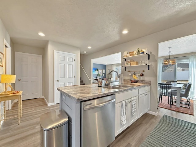 kitchen featuring dishwasher, light wood-type flooring, a textured ceiling, white cabinetry, and a sink