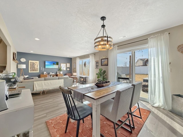 dining room with a chandelier, visible vents, a textured ceiling, and wood finished floors