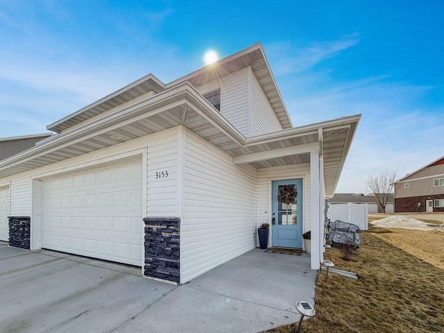 exterior space with a garage, stone siding, and concrete driveway