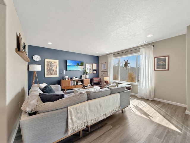 living room featuring visible vents, a textured ceiling, wood finished floors, recessed lighting, and baseboards