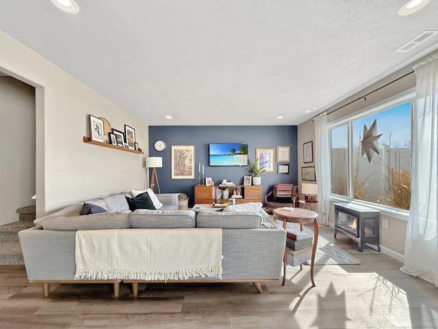 living area with recessed lighting, light wood-style floors, visible vents, and a textured ceiling