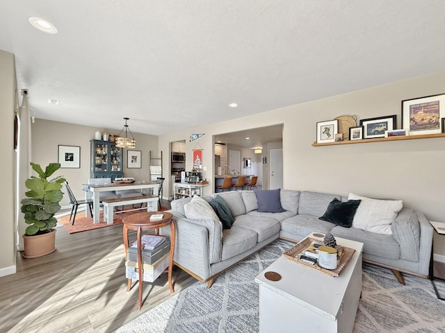 living area with a chandelier, recessed lighting, light wood-style flooring, and baseboards