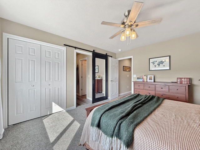 bedroom with a barn door, a closet, carpet flooring, baseboards, and ceiling fan