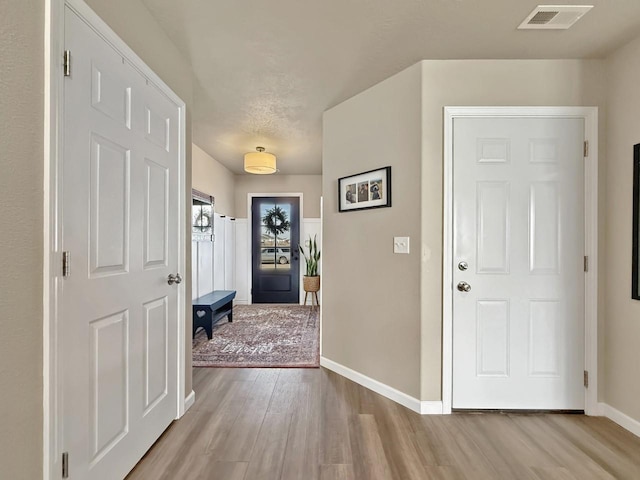 foyer entrance featuring baseboards, visible vents, and light wood-type flooring