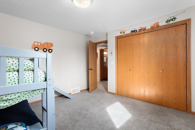 unfurnished bedroom with visible vents, a textured ceiling, baseboards, and carpet floors