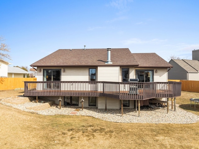 rear view of property featuring fence, roof with shingles, and a wooden deck