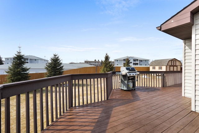 wooden terrace with an outbuilding, fence, a shed, area for grilling, and a residential view