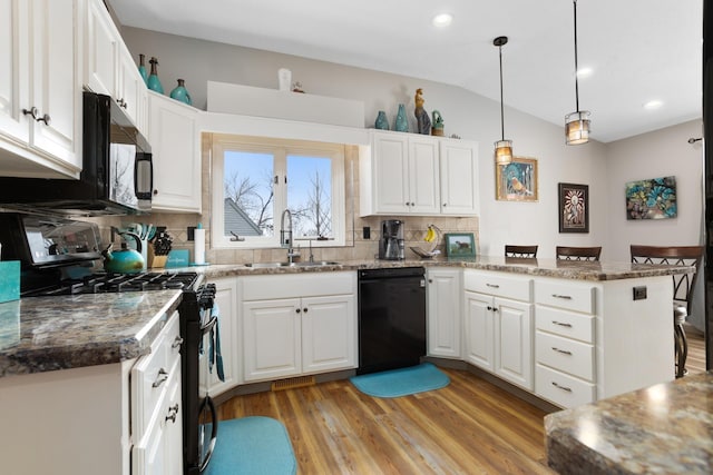 kitchen with a peninsula, a sink, black appliances, vaulted ceiling, and white cabinets