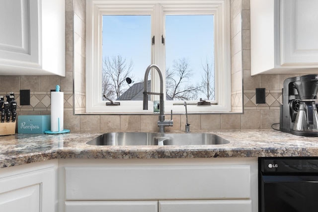 kitchen with a sink, tasteful backsplash, and white cabinets