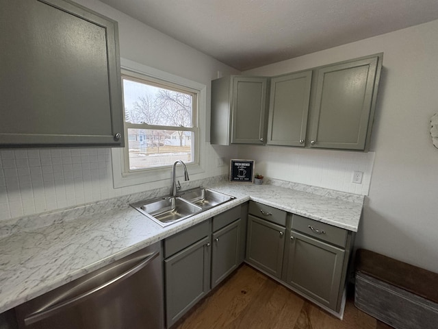 kitchen featuring gray cabinets, a sink, stainless steel dishwasher, light countertops, and decorative backsplash