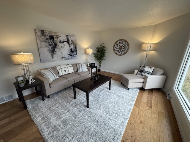 living area featuring visible vents, baseboards, and wood finished floors