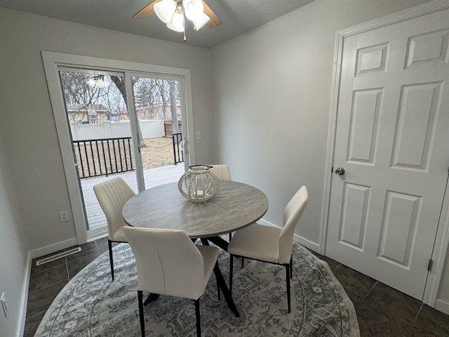 dining room featuring dark tile patterned floors, visible vents, baseboards, and ceiling fan