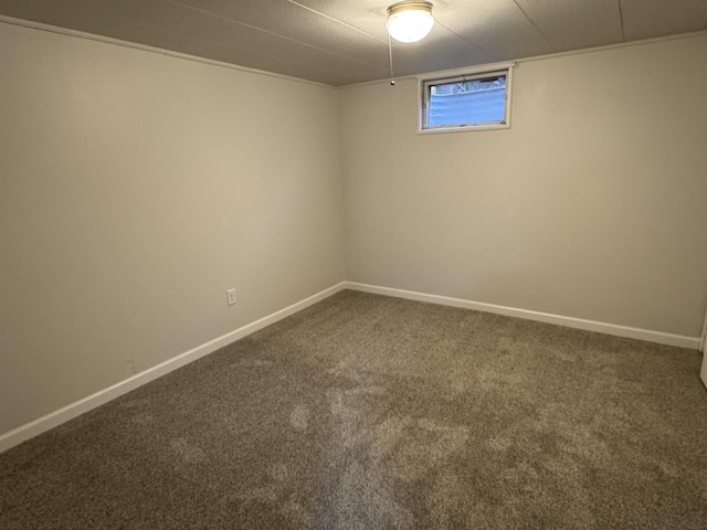 basement featuring baseboards and dark carpet