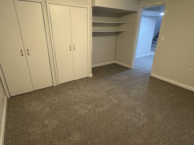 unfurnished bedroom featuring baseboards, two closets, and dark carpet