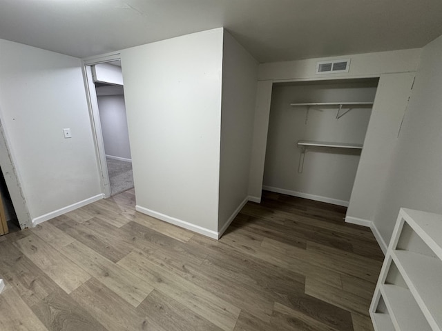 unfurnished bedroom featuring visible vents, baseboards, and wood finished floors