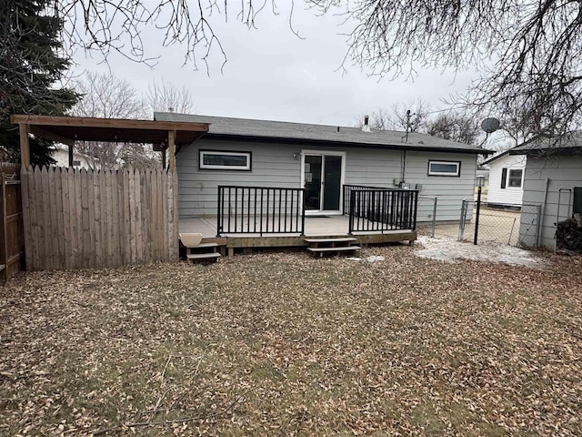 rear view of property featuring a deck and fence