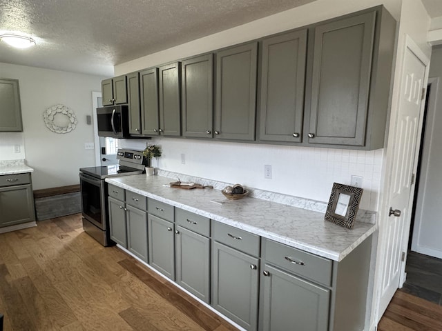 kitchen featuring appliances with stainless steel finishes, dark wood-style floors, gray cabinets, and light countertops