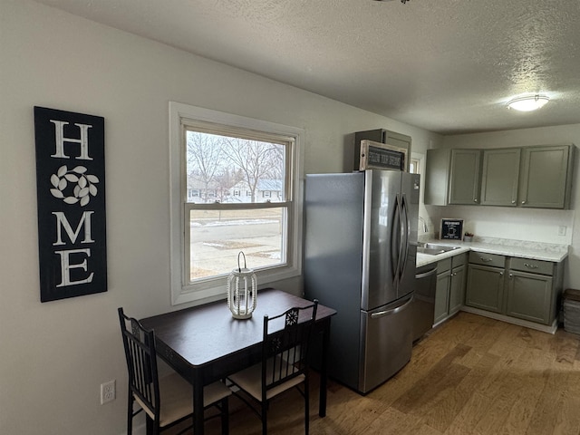 kitchen featuring wood finished floors, gray cabinetry, stainless steel appliances, light countertops, and a textured ceiling