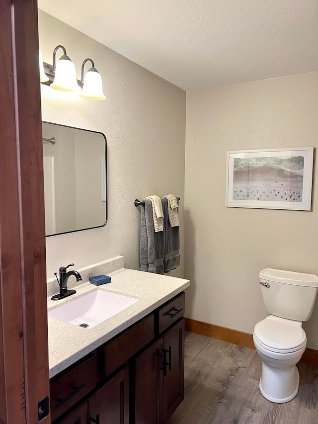 80 Twin Oaks Shr Unit 34, Bottineau, ND 58318 - half bathroom featuring toilet, wood finished floors, baseboards, and vanity
