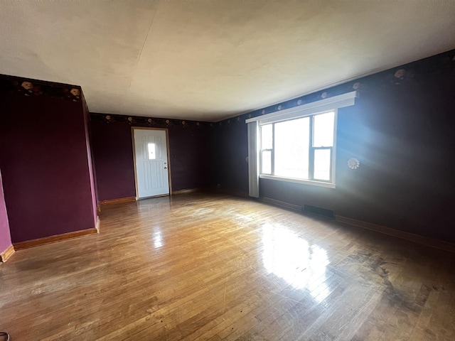 unfurnished room featuring baseboards, visible vents, and light wood-type flooring