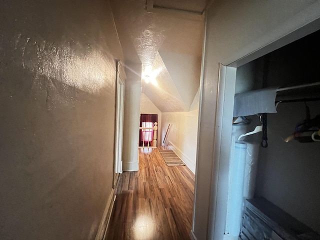 hall with baseboards, lofted ceiling, and wood finished floors