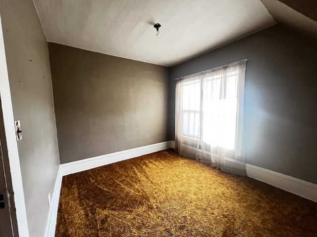 carpeted empty room featuring baseboards and lofted ceiling