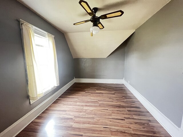 additional living space with baseboards, vaulted ceiling, wood finished floors, and a ceiling fan
