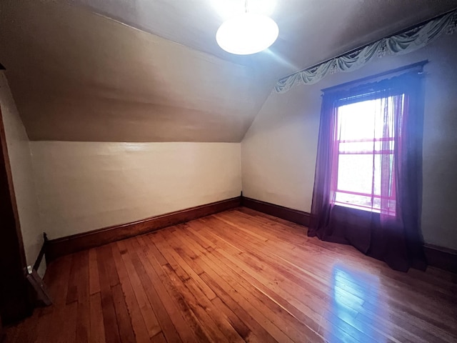 bonus room with baseboards, vaulted ceiling, and light wood-style flooring