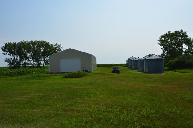view of yard featuring driveway, a detached garage, an outdoor structure, and a pole building