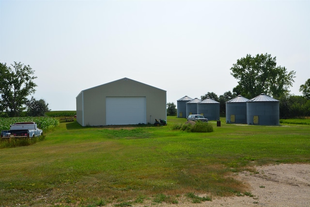 view of yard with a pole building, an outbuilding, driveway, and a detached garage