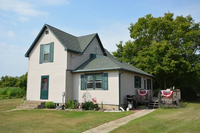 view of front facade with a shingled roof, a front lawn, and a deck