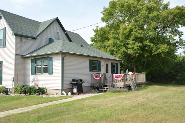 view of property exterior with roof with shingles, a deck, and a yard