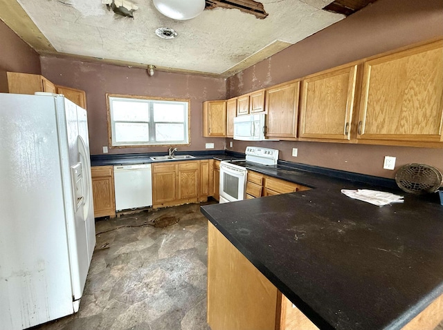 kitchen featuring a sink, dark countertops, a peninsula, and white appliances