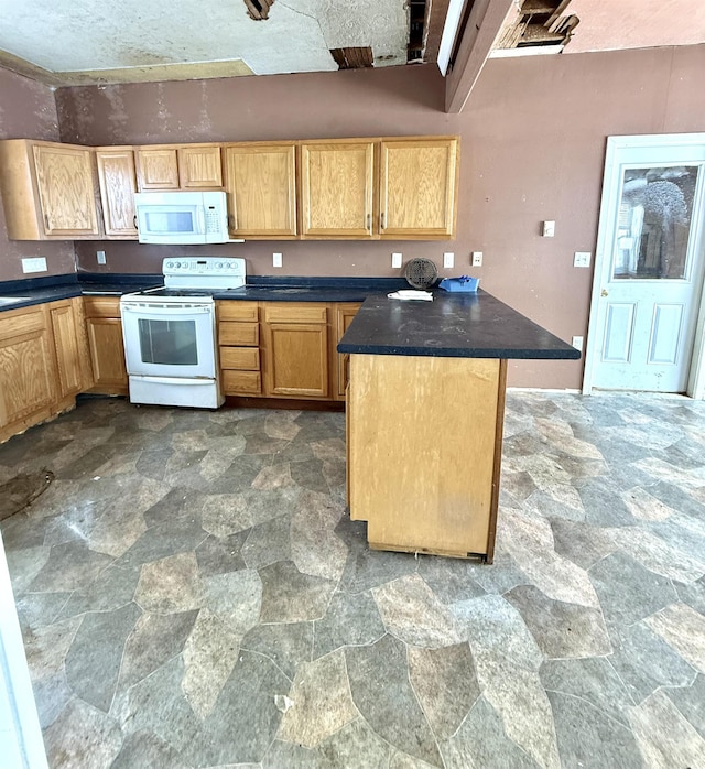 kitchen featuring stone finish floor, white appliances, dark countertops, and a peninsula