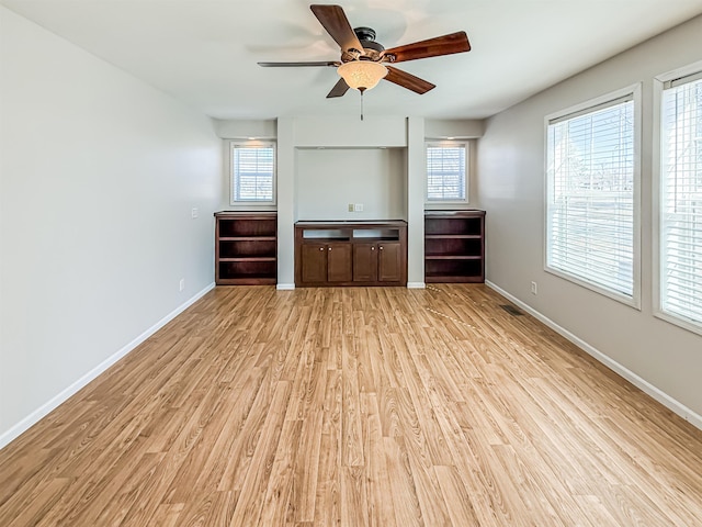 unfurnished living room with baseboards, a ceiling fan, a healthy amount of sunlight, and light wood-type flooring