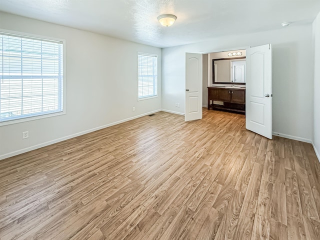 unfurnished bedroom featuring baseboards, light wood finished floors, and a textured ceiling