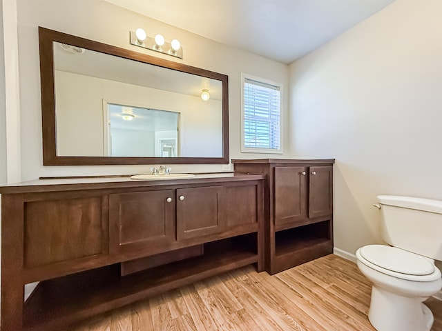 bathroom with baseboards, toilet, vanity, and wood finished floors