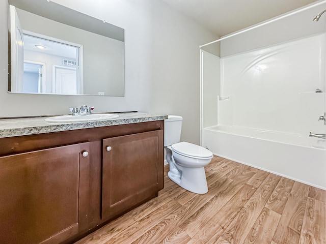 bathroom with visible vents, wood finished floors, toilet, vanity, and shower / bathing tub combination