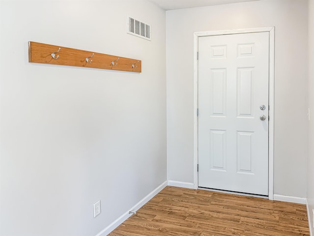 doorway to outside with wood finished floors, baseboards, and visible vents